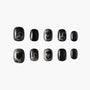 Set of black press-on nails with silver glitter and abstract heart accents, displayed on white background.