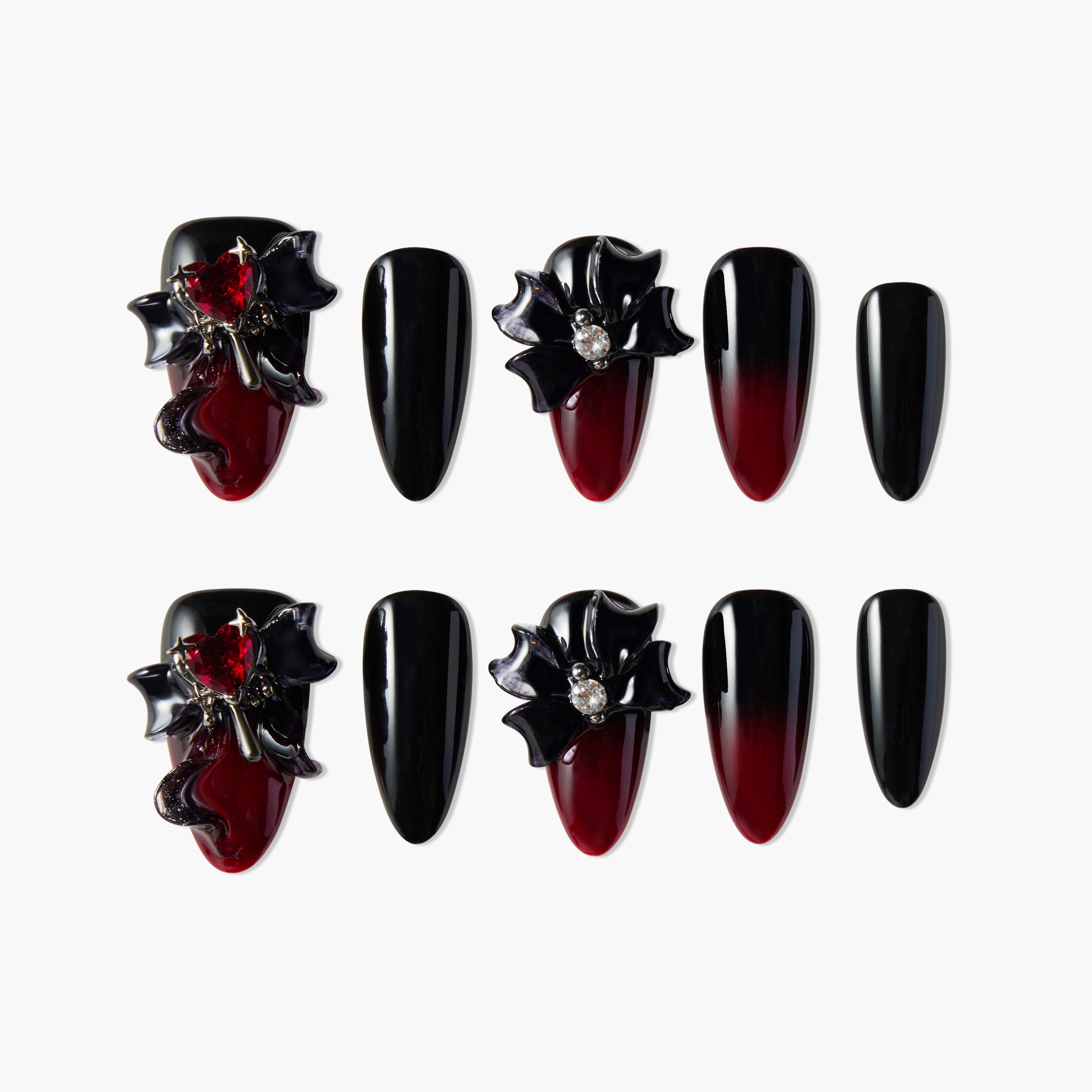 Black and red ombre press-on nails with 3D bows, gems, and heart accents on a white background.
