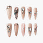 Nude press-on nails with 3D rhinestones, floral art, glitter, and gem embellishments.