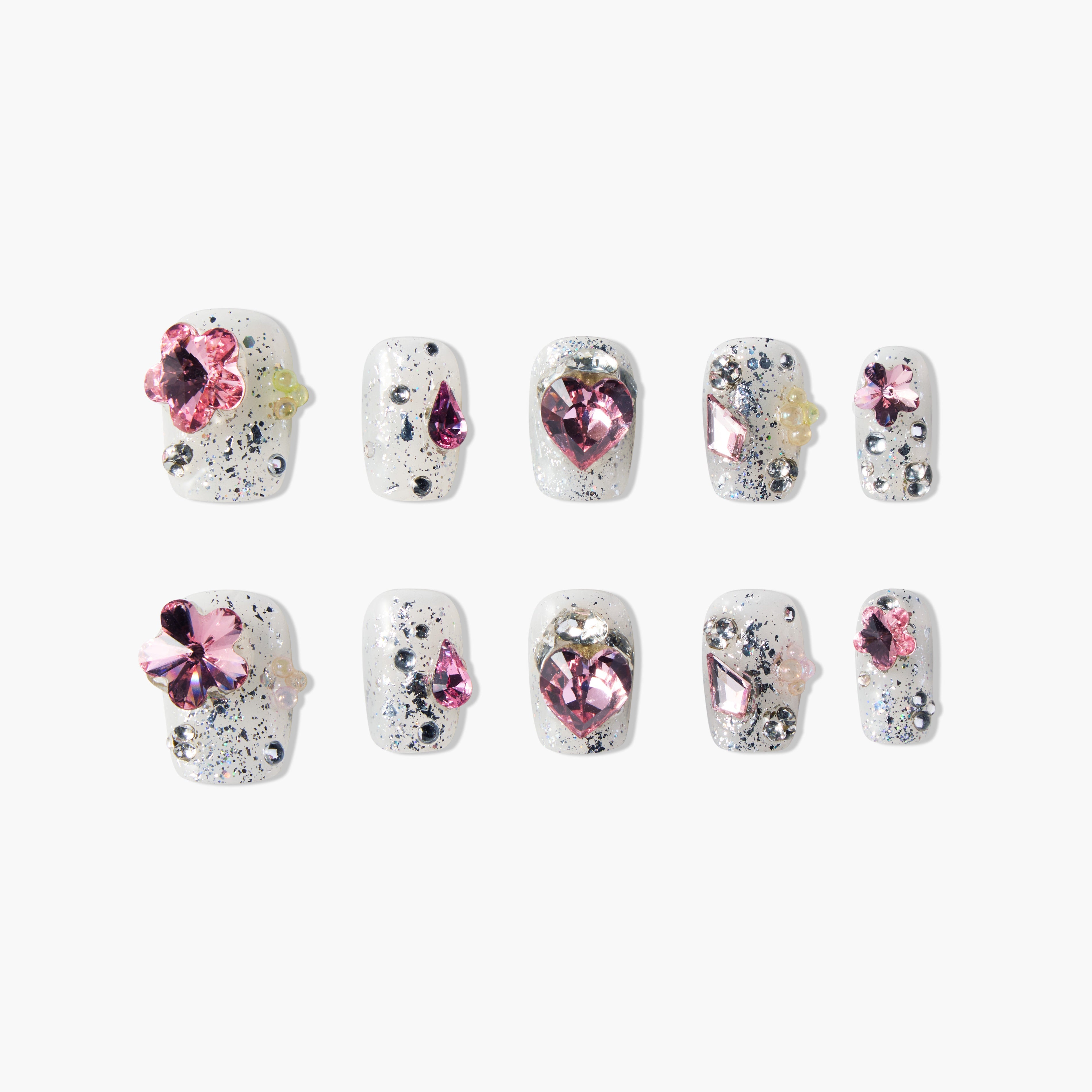 Handmade press-on nails with white base, black splatter, and pink gemstone accents