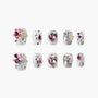 Handmade press-on nails with white base, black splatter, and pink gemstone accents
