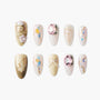 Handmade press-on nails with pink gems, gold accents, floral and pearl decorations, and abstract art.