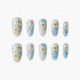 Blue and silver press-on nails with 3D yellow flowers and rhinestone accents, glossy finish