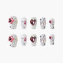 White glitter press-on nails with pink gemstone accents and 3D floral designs