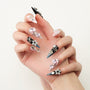 Hand with long press-on nails featuring 3D gems, pearls, stars, and black and blue accents