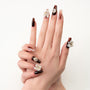 Hand with brown and nude press-on nails, 3D floral accents and rhinestone designs