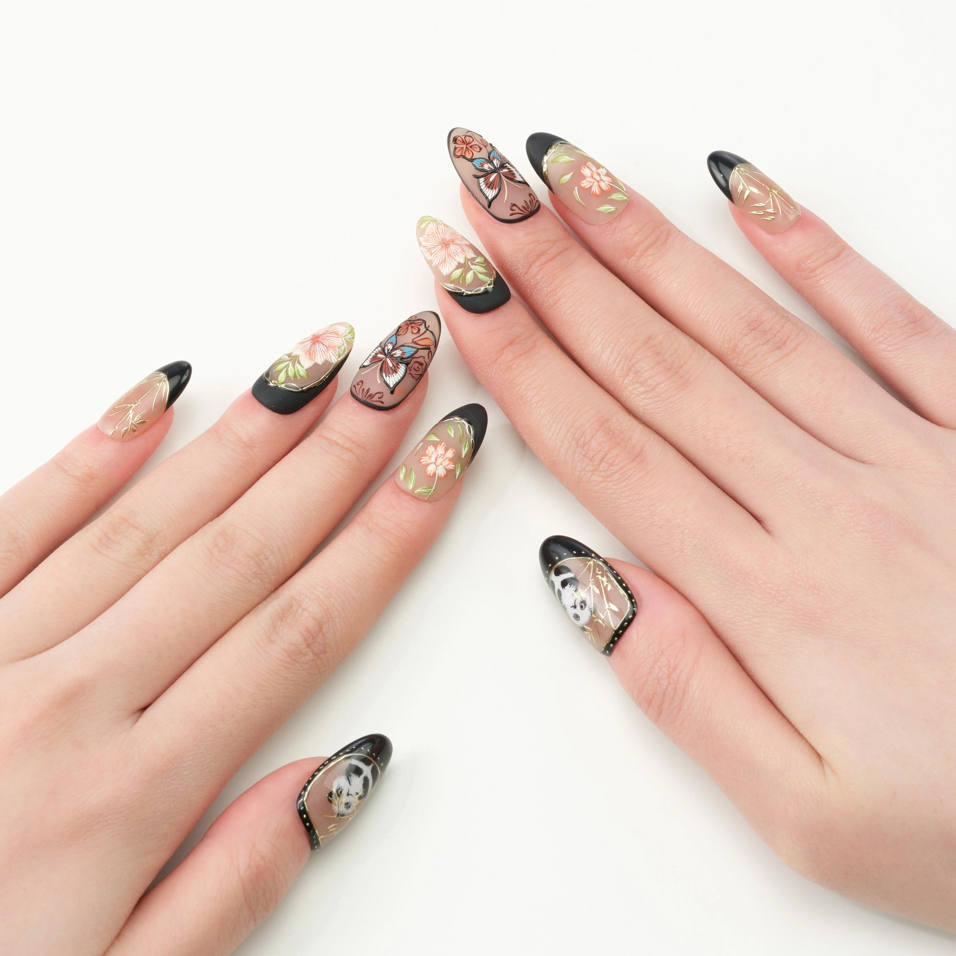 Almond-shaped press-on nails with black tips, floral designs, and butterfly accents