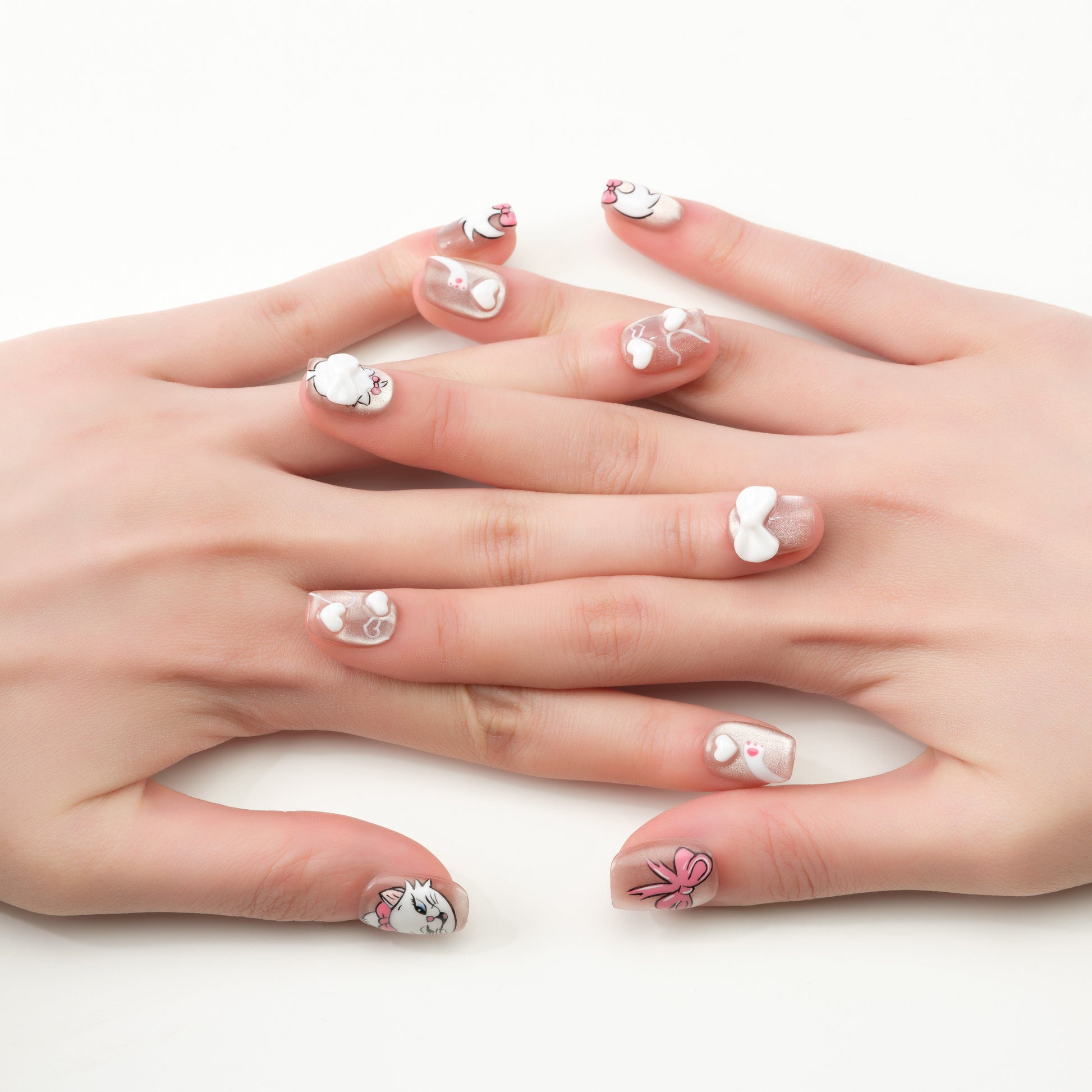 Handmade press-on nails with white and pink 3D bows, cartoon cats, and heart designs on a nude base.