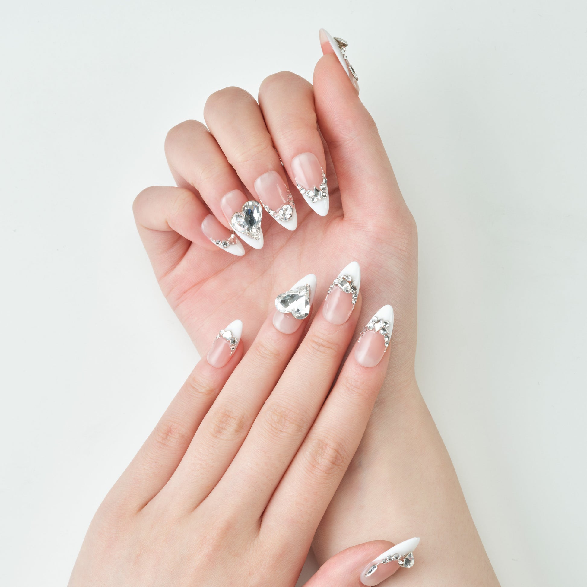 Long stiletto press-on nails with white tips and large silver rhinestone accents