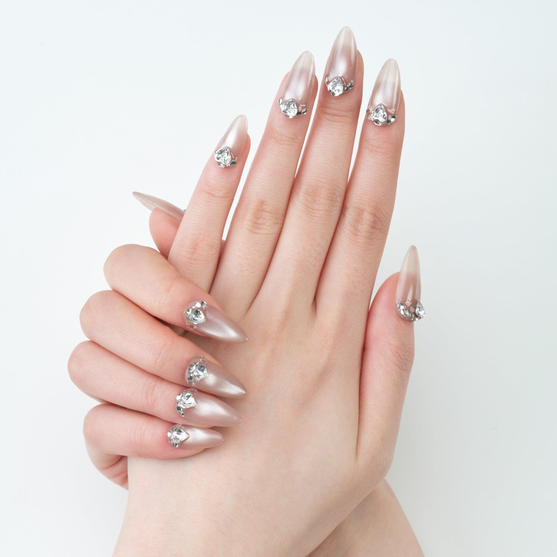Long almond press-on nails with a pearlescent finish and large rhinestone accents
