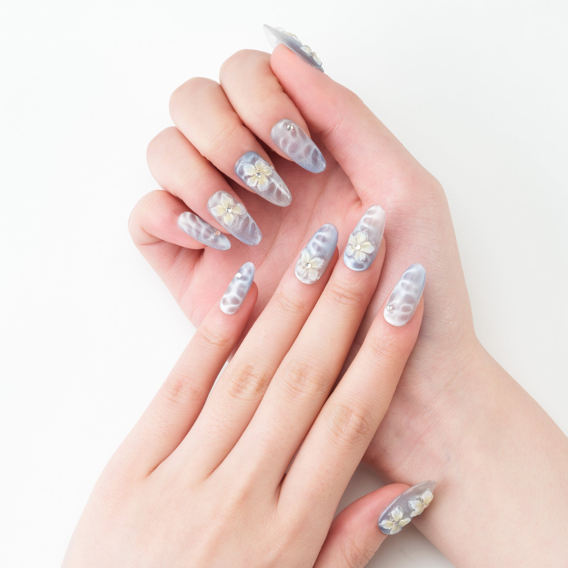 Handmade press-on nails in silver with 3D white floral designs and rhinestone accents