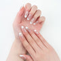 Hand with almond-shaped press-on nails featuring white French tips and delicate lace designs