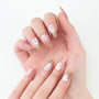 Hand with long almond-shaped press-on nails featuring pink ombre and white floral designs