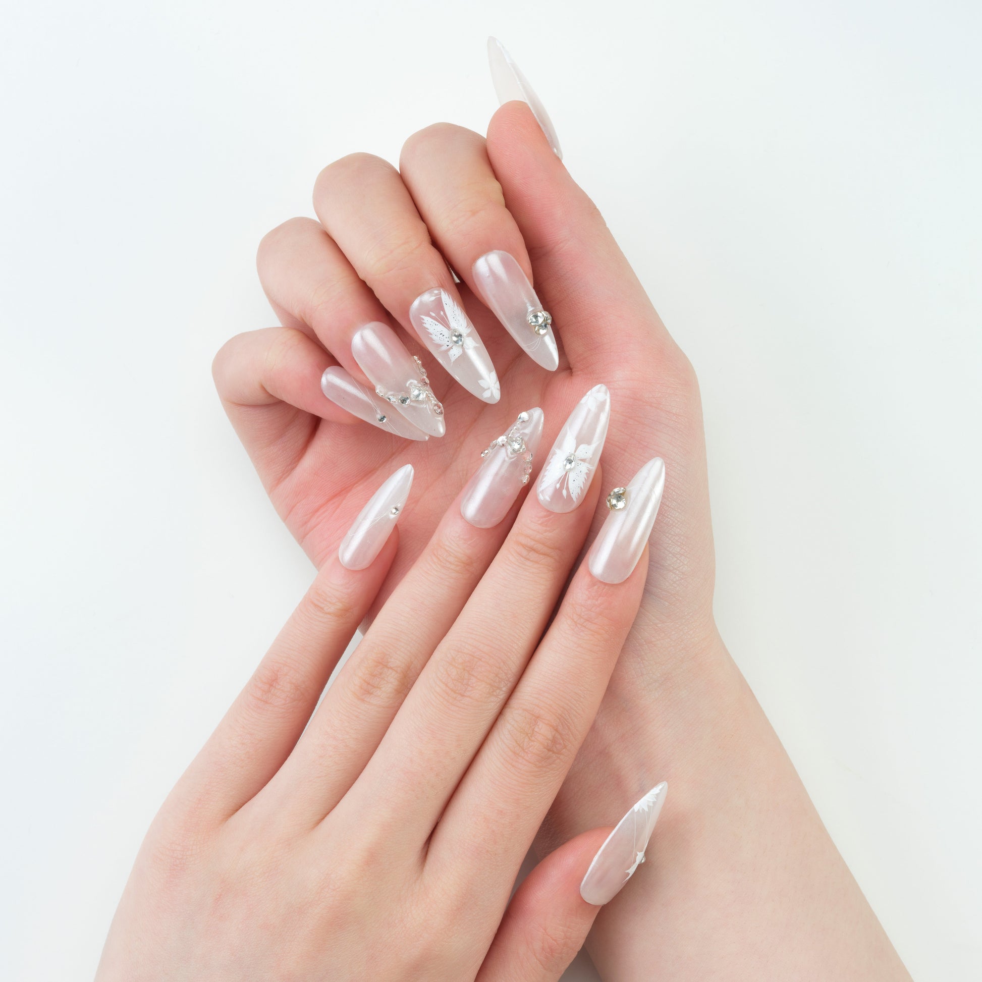 Hand with long stiletto press-on nails featuring white butterfly designs and rhinestones
