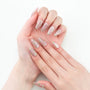 Hand with long, almond-shaped press-on nails featuring pink base and floral designs