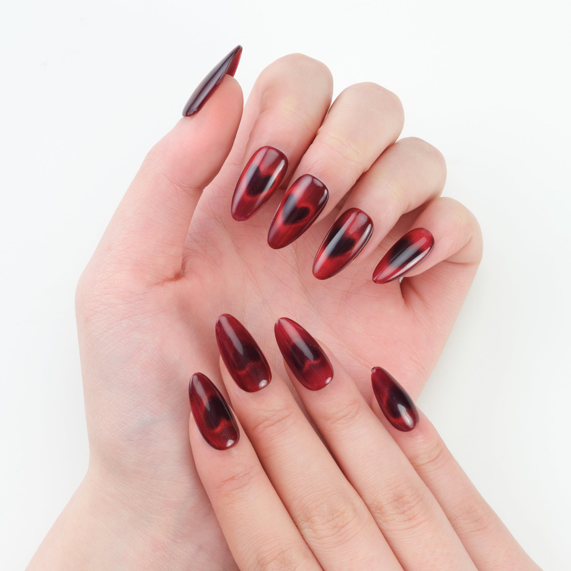 Almond-shaped burgundy red press-on nails with glossy, marbled design on both hands