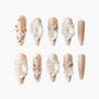 Handmade nude press-on nails with 3D white flowers, pearl and gold bead accents, elegant nail art