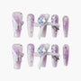 Handmade lavender press-on nails with butterfly, bows, floral design, and gemstone accents.