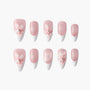 Pink and white French tip press-on nails with 3D floral and pearl accents, arranged on white background