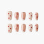 Handmade press-on nails with nude and blush tones, red heart designs, and rhinestone accents