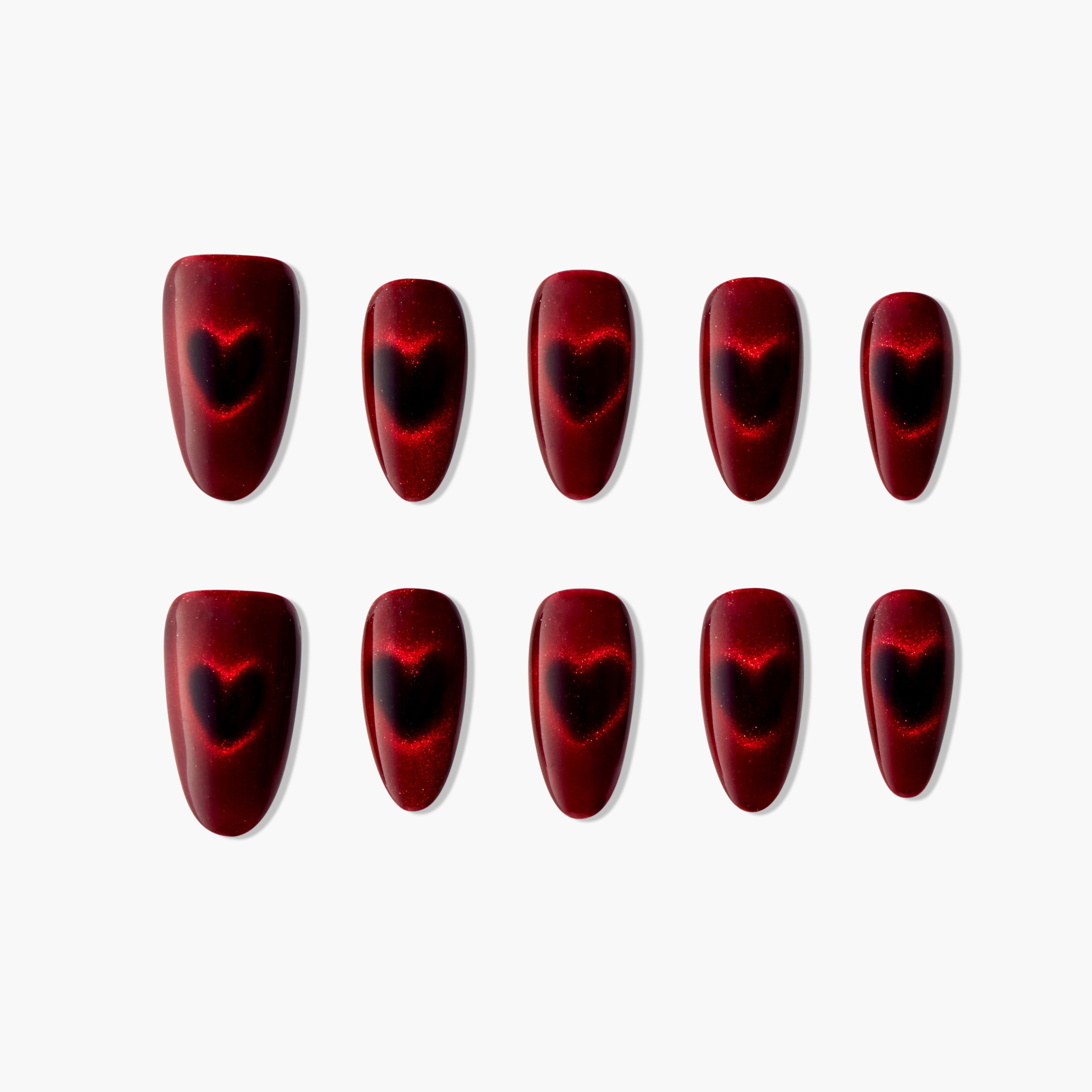 Red press-on nails with black heart design, glossy finish, arranged on white background.
