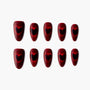 Red press-on nails with black heart design, glossy finish, arranged on white background.