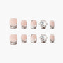 Handmade press-on nails with pink base, silver glitter tips, pearls, and floral rhinestones