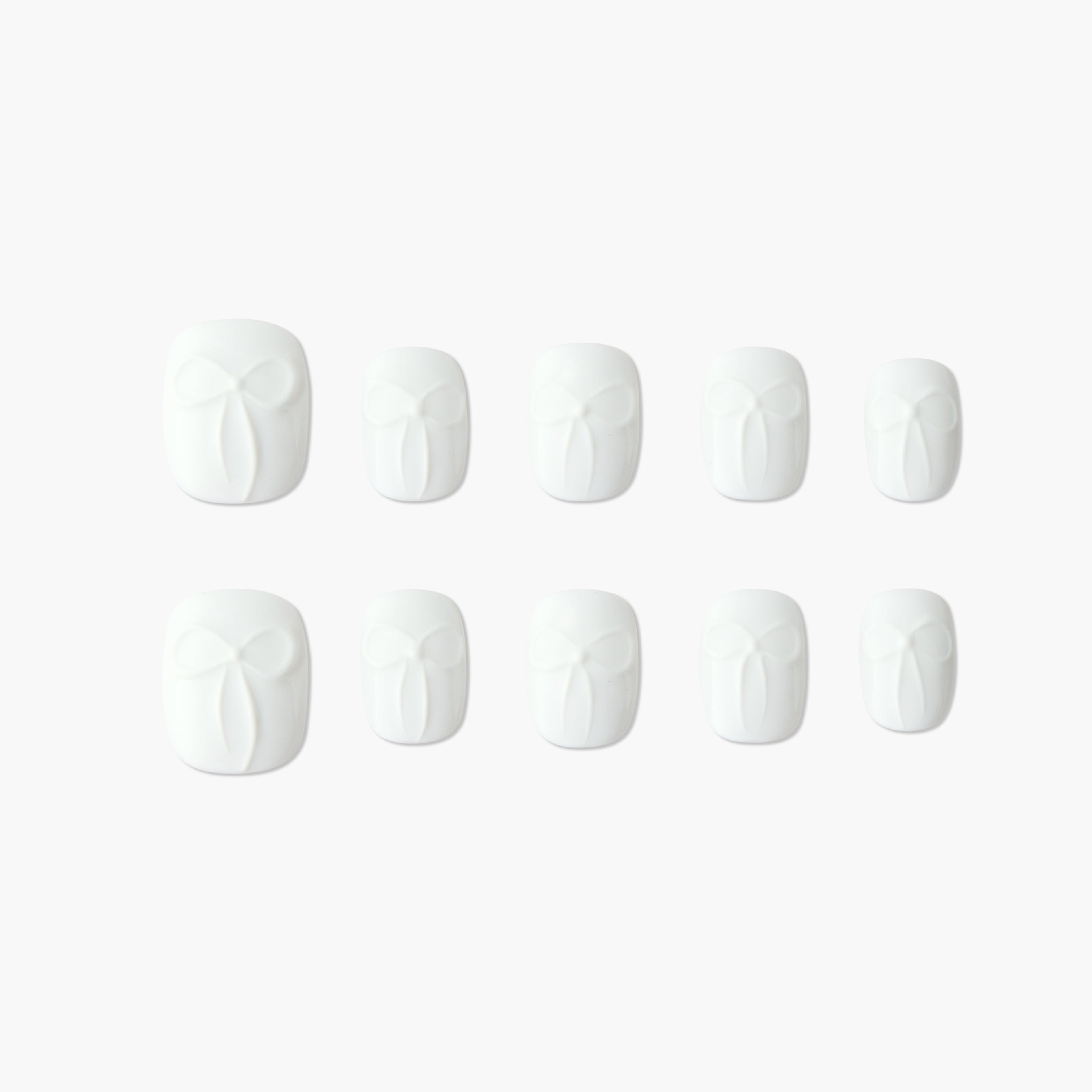 Set of white press-on nails with embossed bow design, displayed on a plain background.