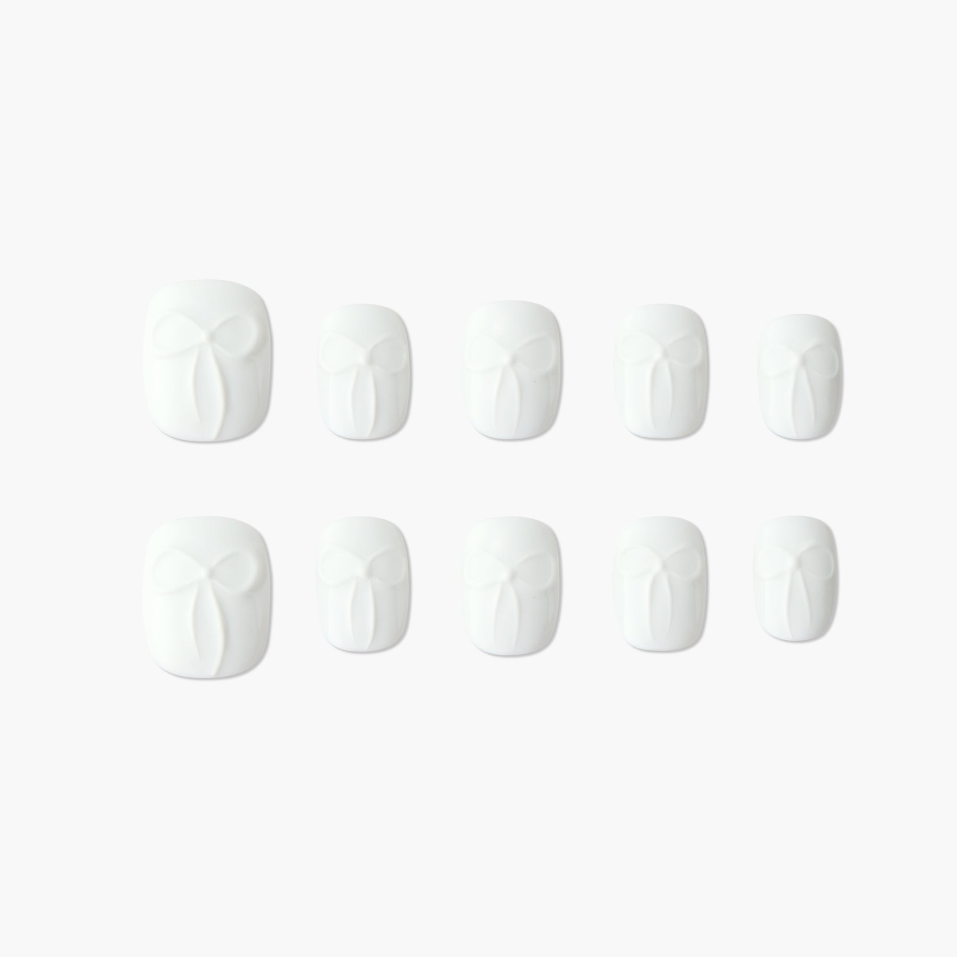 Set of white press-on nails with embossed bow design, displayed on a plain background.