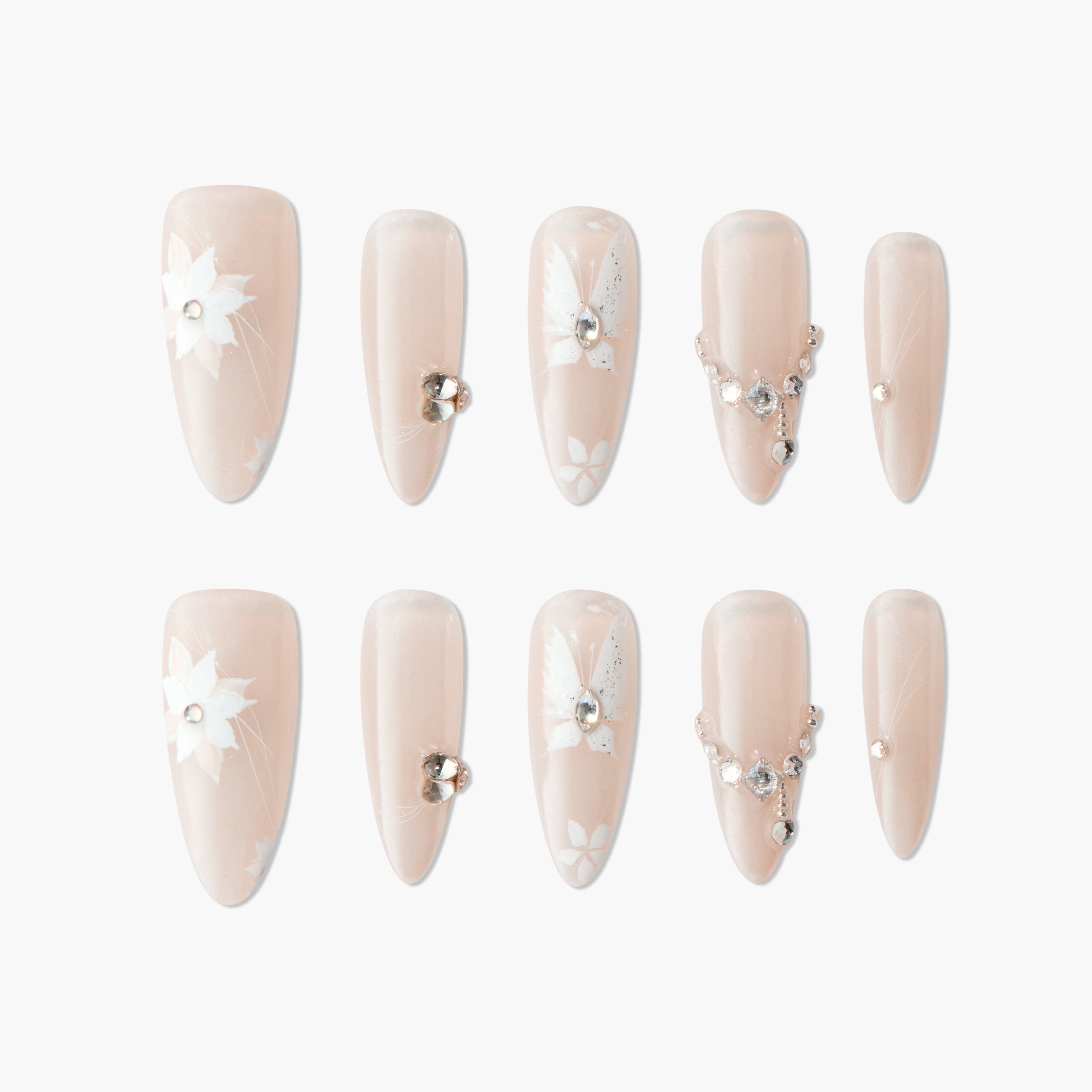 Nude press-on nails with white floral designs and rhinestone accents, elegant manicure set