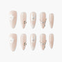 Nude press-on nails with white floral designs and rhinestone accents, elegant manicure set