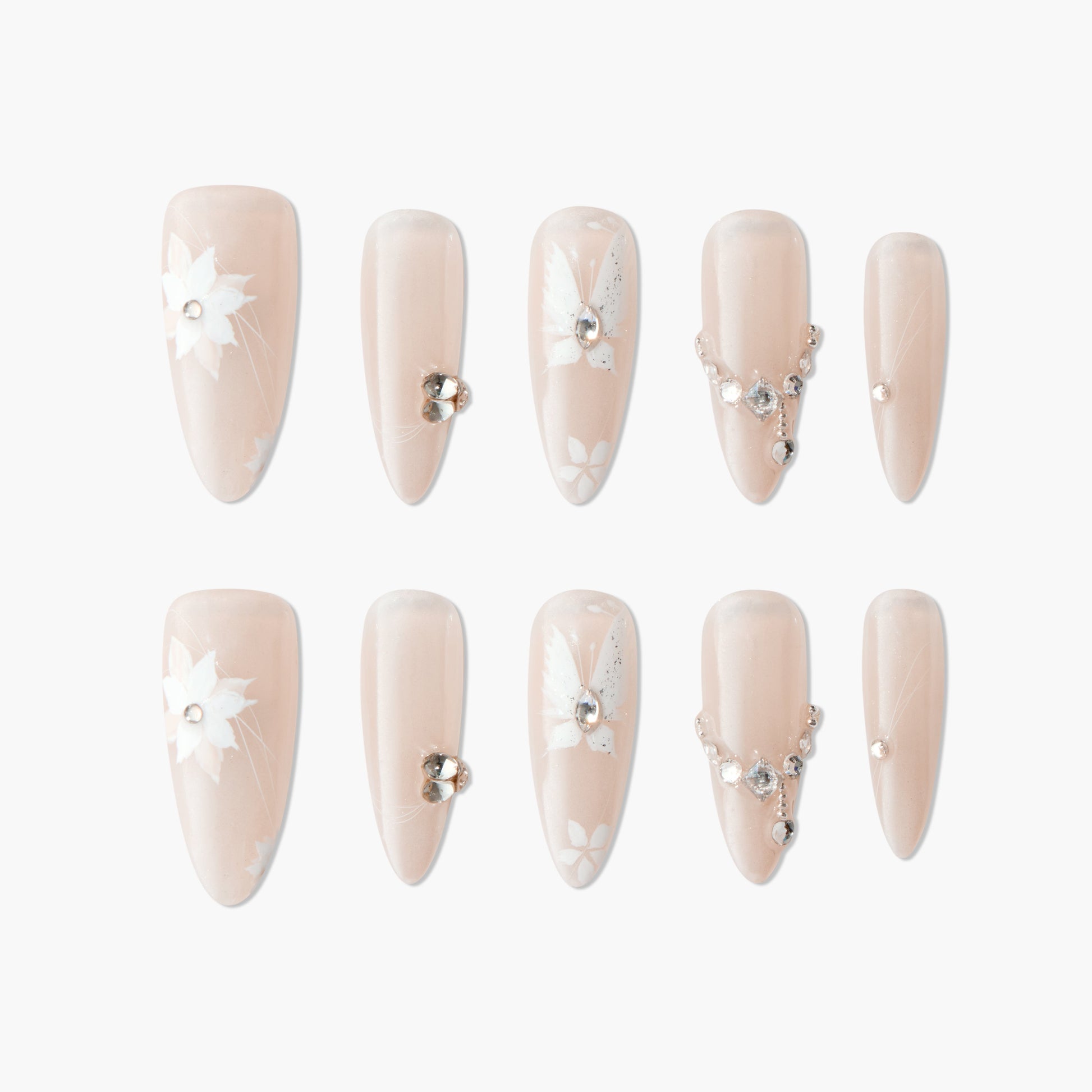 Nude press-on nails with white floral designs and rhinestone accents, elegant manicure set