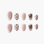 Pink press-on nails with black polka dots and bow design, pearl accent, glossy finish
