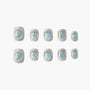 Set of silver glitter press-on nails with iridescent blue accents on a white background