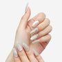 Hand with long almond-shaped press-on nails in pale shades, decorated with snowflake and gold star designs.