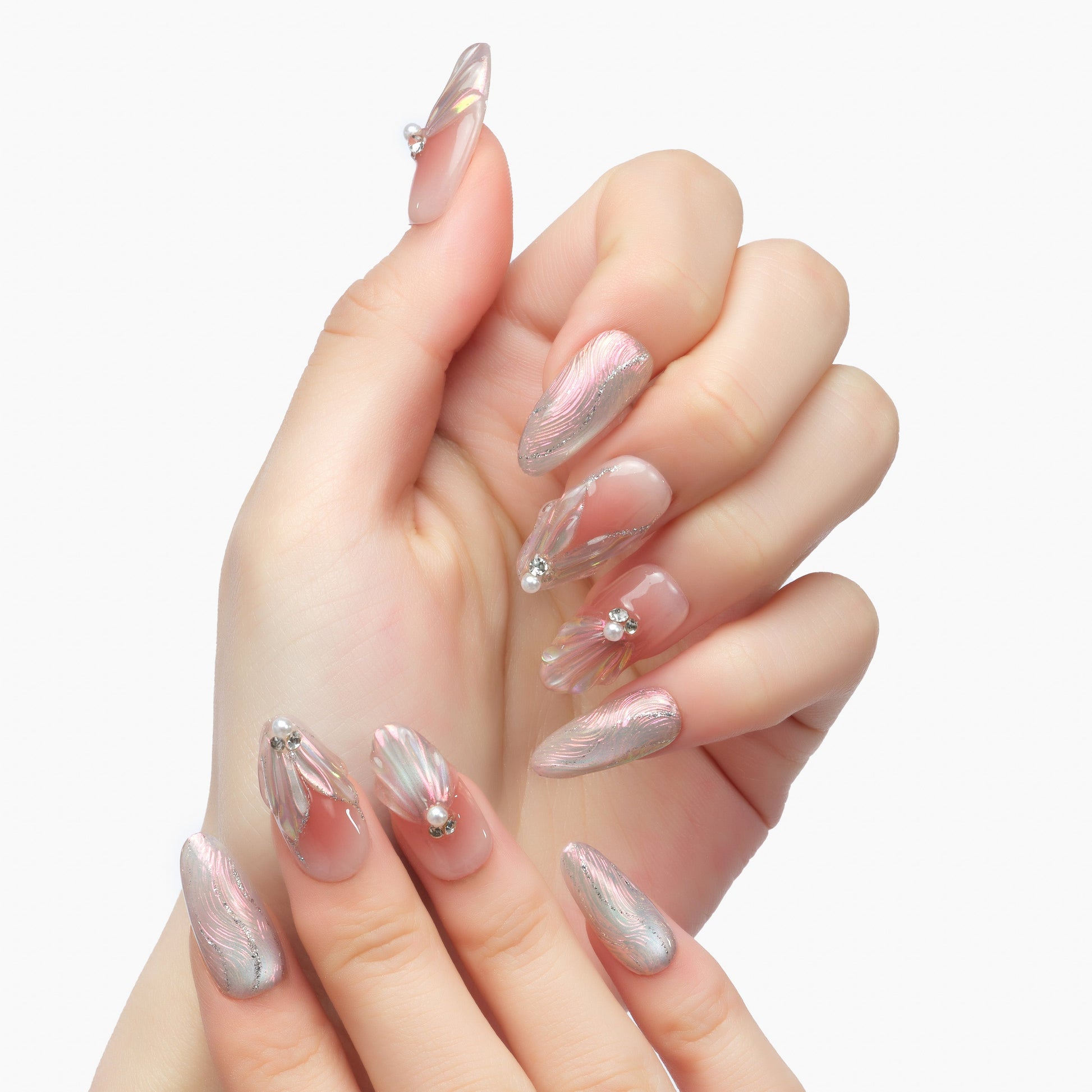 Hand with long, iridescent press-on nails featuring 3D floral designs and rhinestones