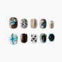 Handmade press-on nails with unique abstract, pearl, and gemstone designs on a white background