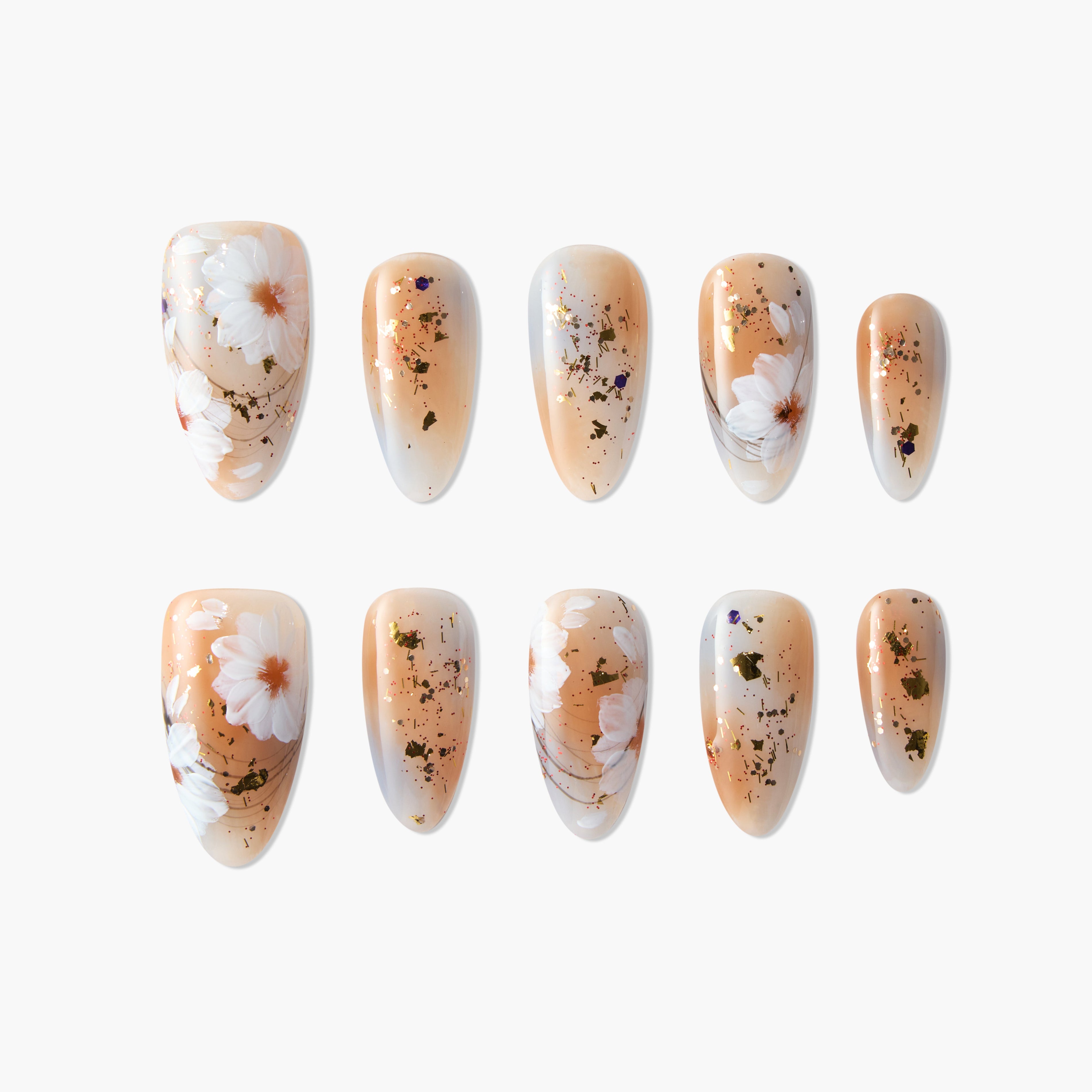 Handmade press-on nails with nude base, white daisy floral design, and gold foil accents.