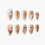 Handmade press-on nails with nude base, white daisy floral design, and gold foil accents.