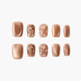Set of brown press-on nails with glossy, quilted, and jeweled 3D designs on white background.