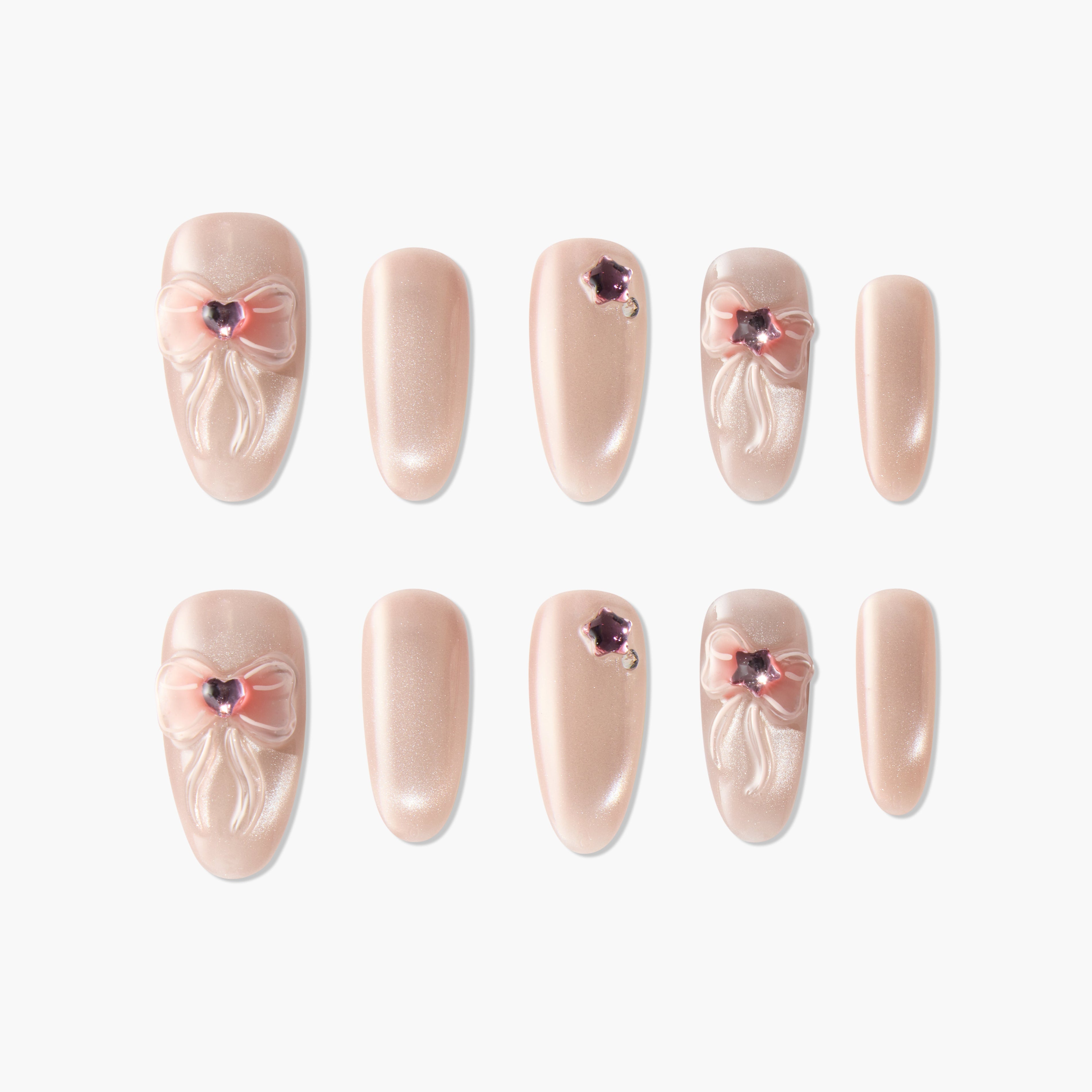 Handmade nude press-on nails with pink 3D bows and gemstone accents
