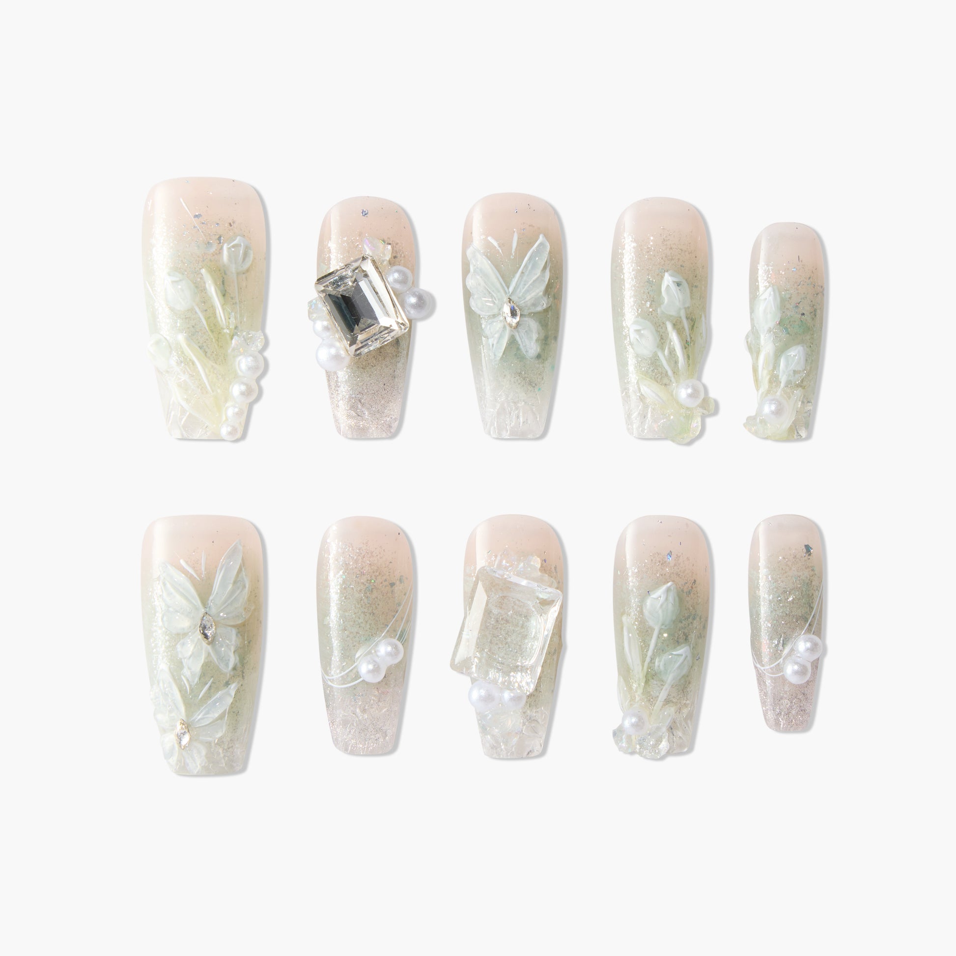 Handmade press-on nails with floral designs, gems, pearls, and soft nude-green gradient.