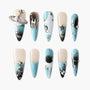 Blue and nude almond-shaped press-on nails with silver star charms, rhinestones, and abstract designs.