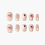 Handmade press-on nails in shimmery nude with pink 3D bows and rhinestone accents