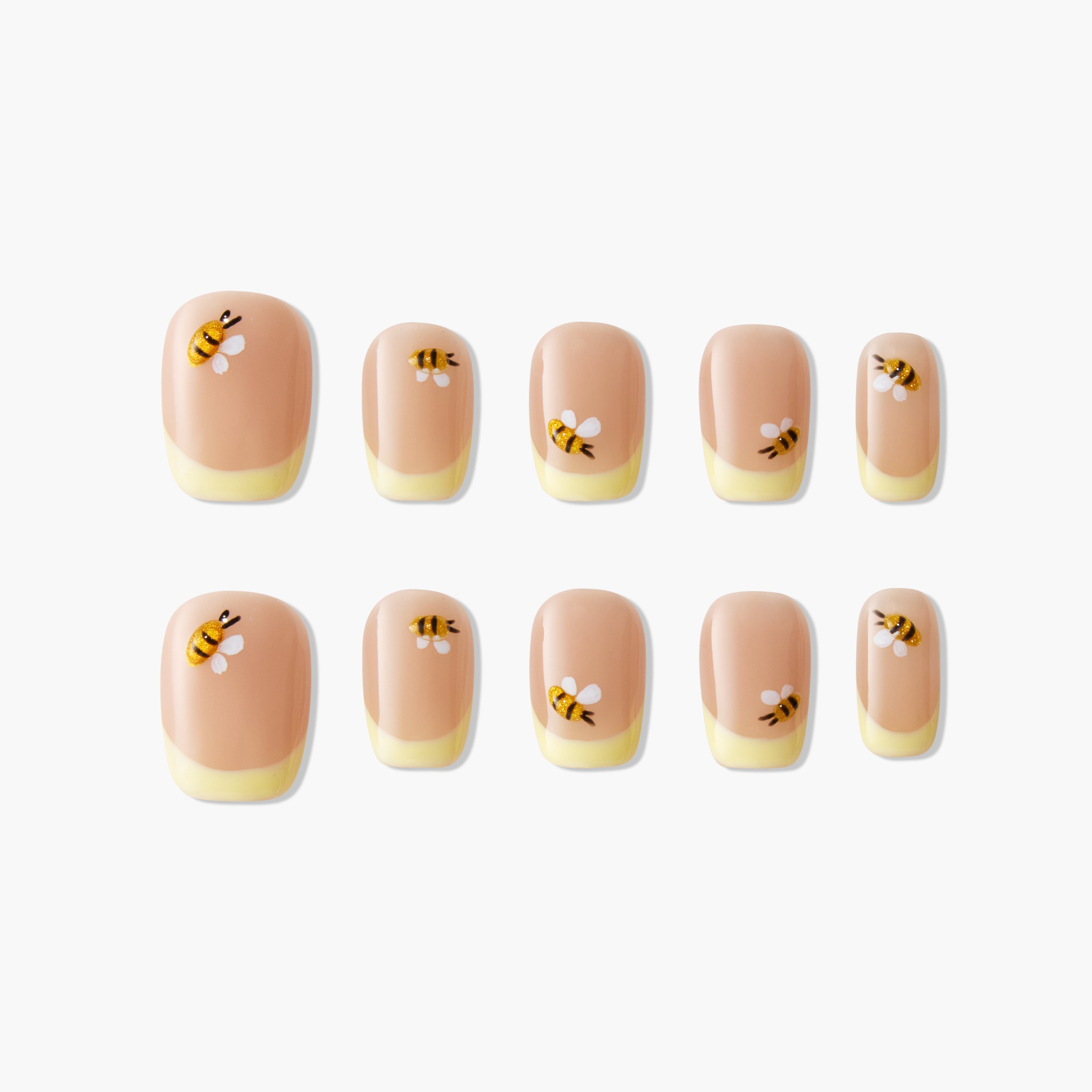 Bee-themed handmade press-on nails with nude and yellow tips, arranged on white background