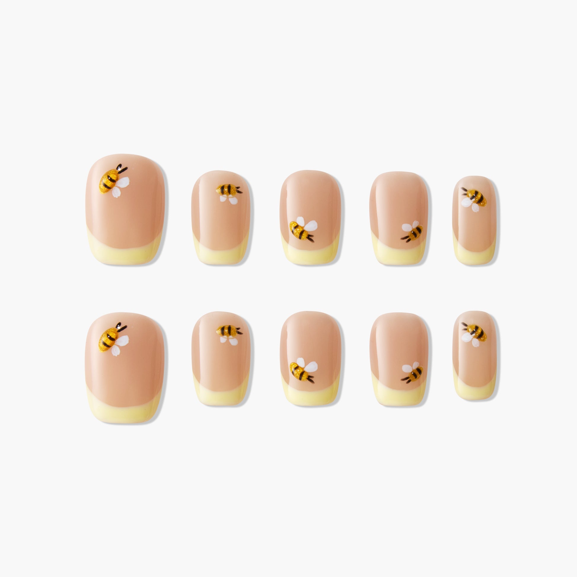 Bee-themed handmade press-on nails with nude and yellow tips, arranged on white background