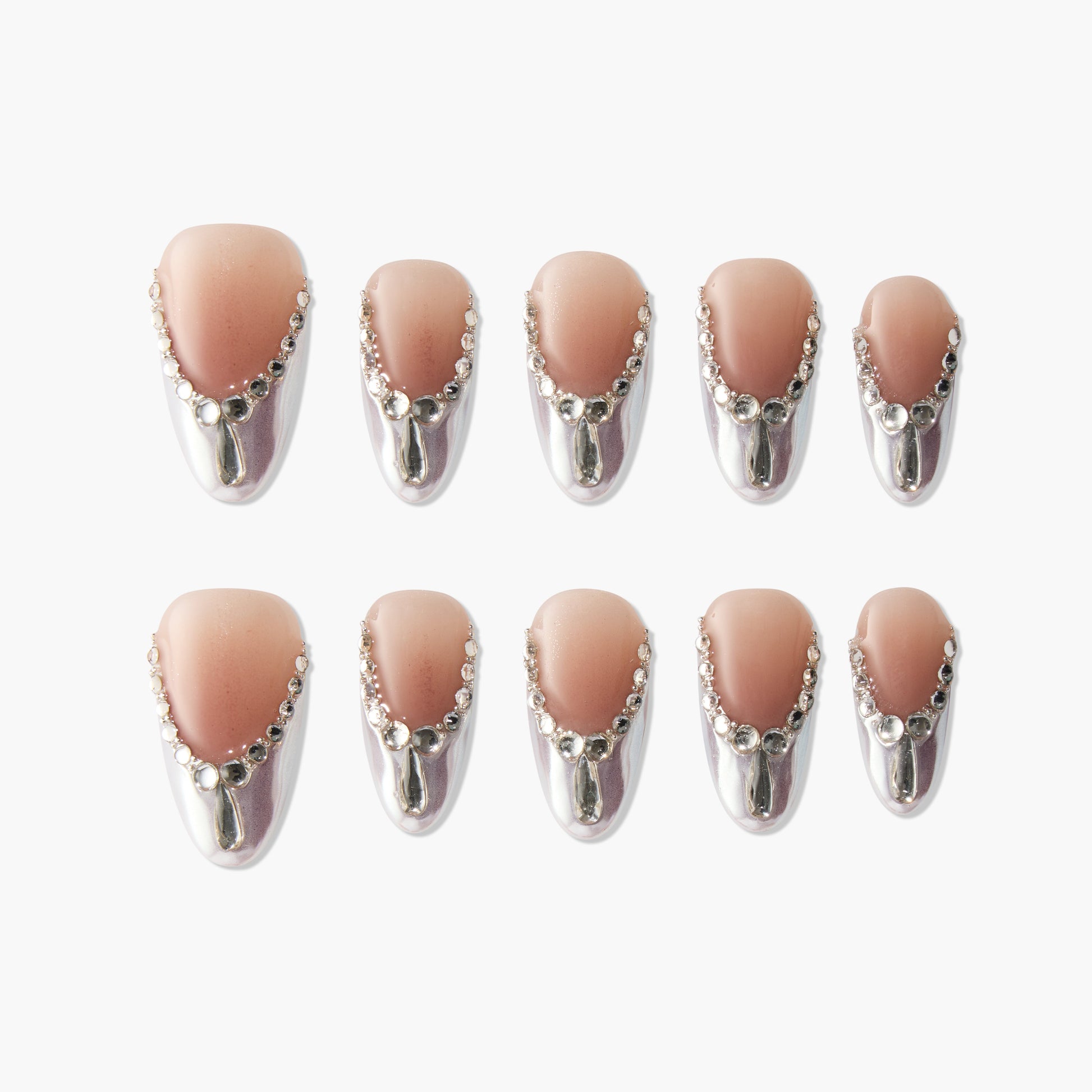 Glossy nude press-on nails with silver chrome tips and rhinestone accents, arranged in rows.