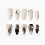 Handmade press-on nails set with nude base, butterfly, flower, and rhinestone designs