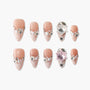 Handmade press-on nails with pink marbled tips, pearl accents, rhinestones, and 3D floral gems