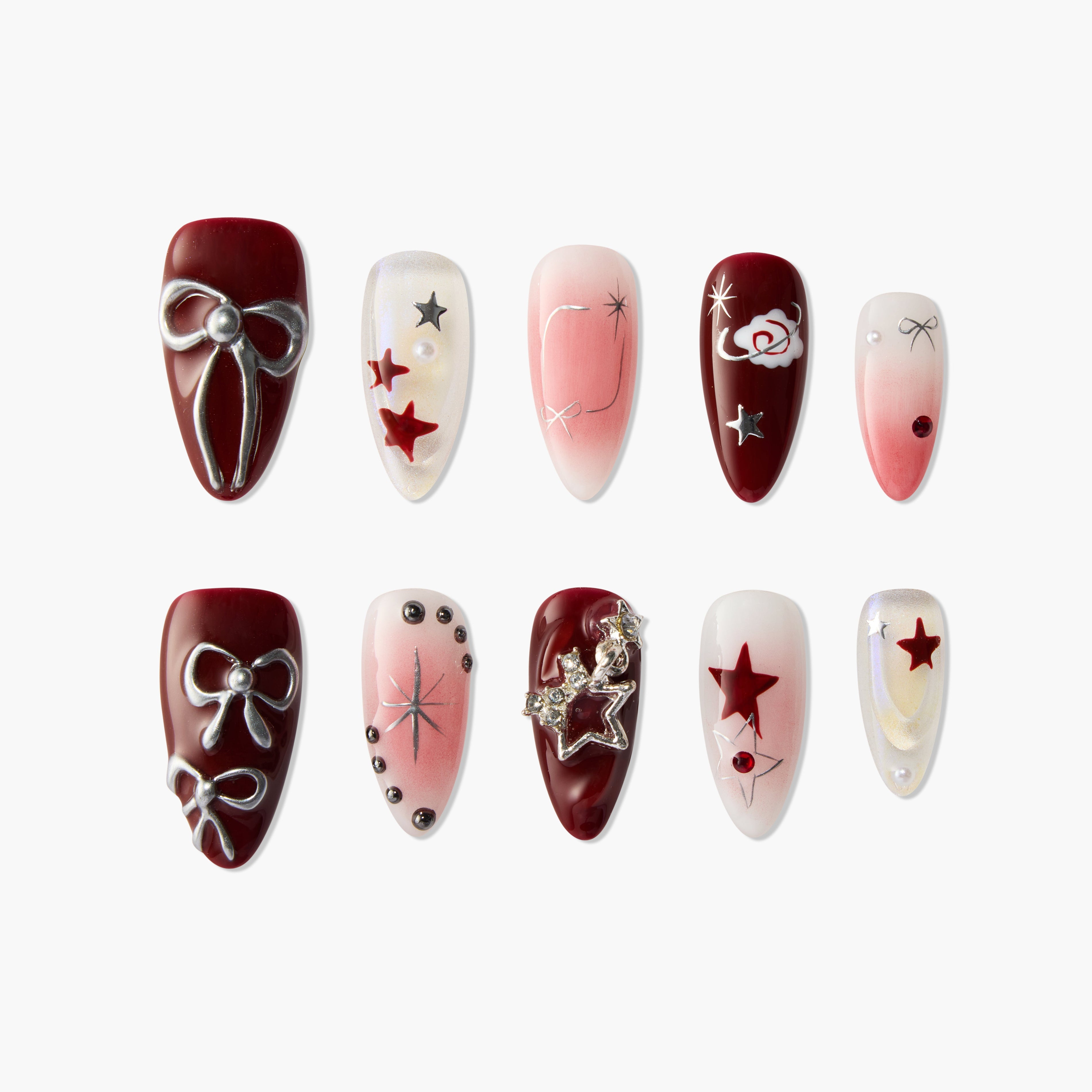 Red and pink press-on nails with star, bow, pearl, and 3D embellishments, arranged on white background